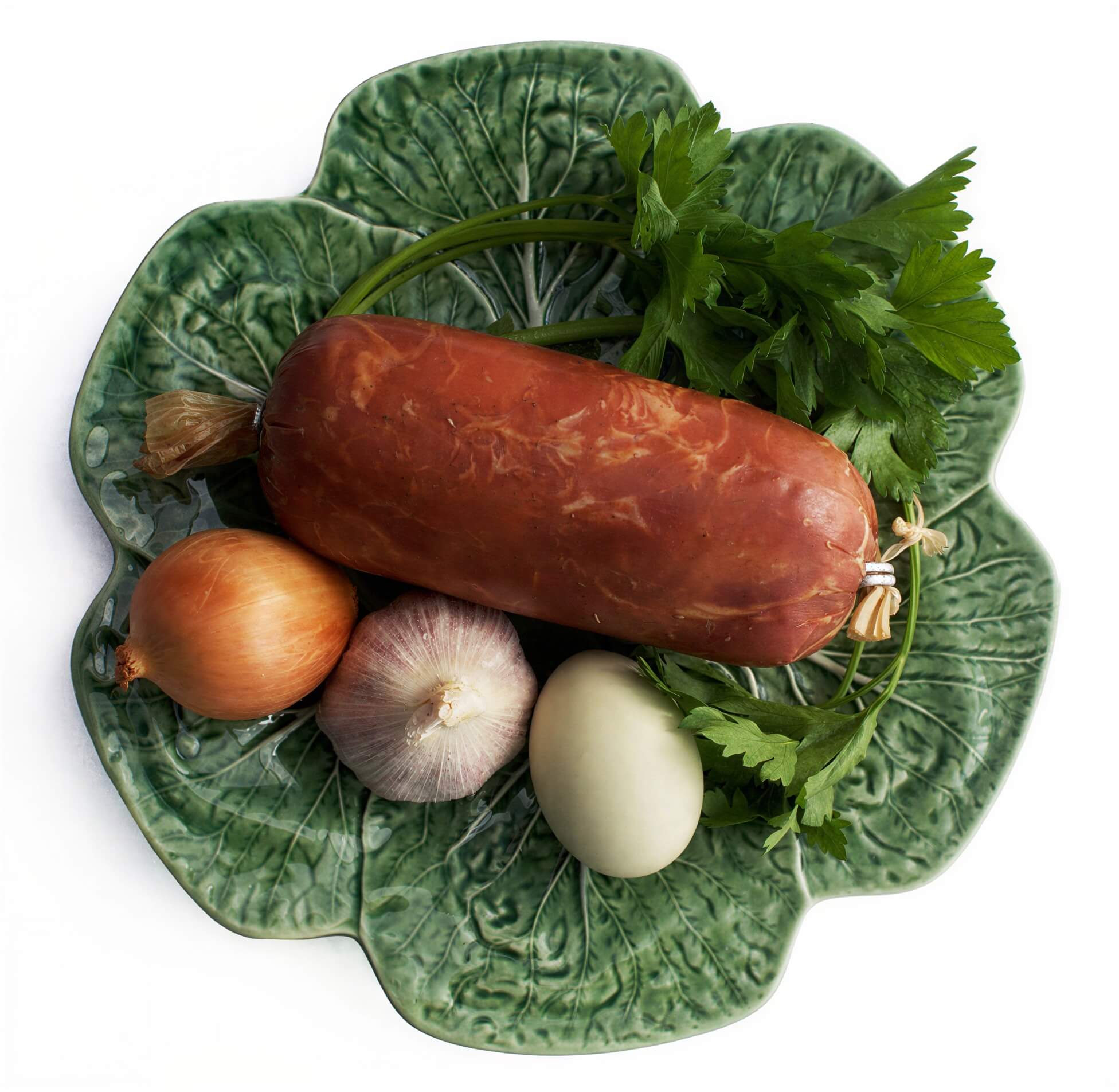 "Salpicão", a traditional Portuguese sausage on a green plate with garlic onions and parsley