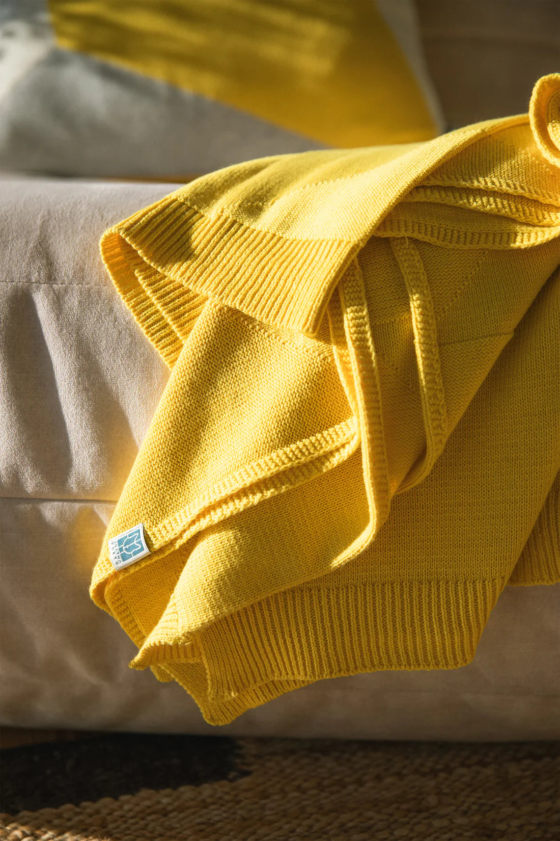 Yellow blanket draped over a beige surface with a visible brand tag.