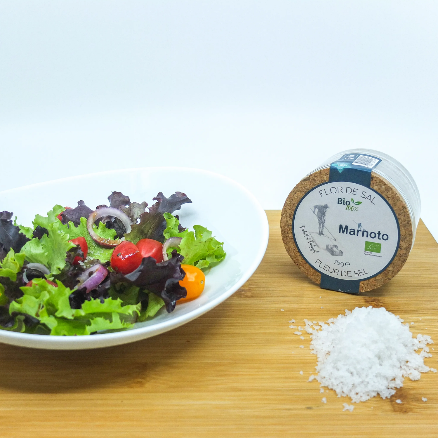 Salad bowl and salt and a container labeled 'Marnoto' on a wooden surface.