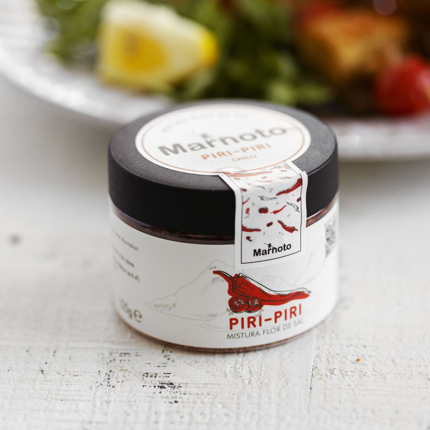 Jar of Marnoto Piri-Piri seasoning on a table with a blurred background