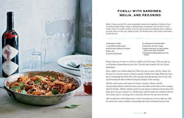 Pasta dish with a bottle of wine on a table, next to a recipe card.