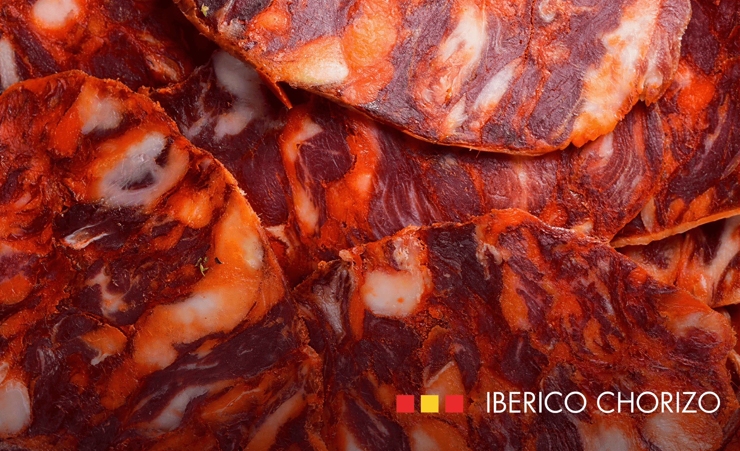 Sliced Fermin Iberico chorizo showcasing rich marbling and vibrant red color on a wooden surface.