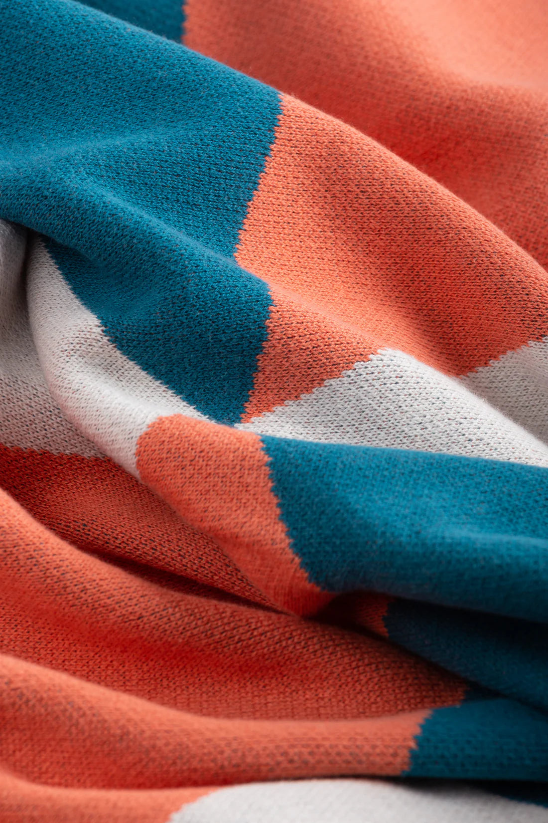 Close-up of a fabric with blue, orange, and white stripes.