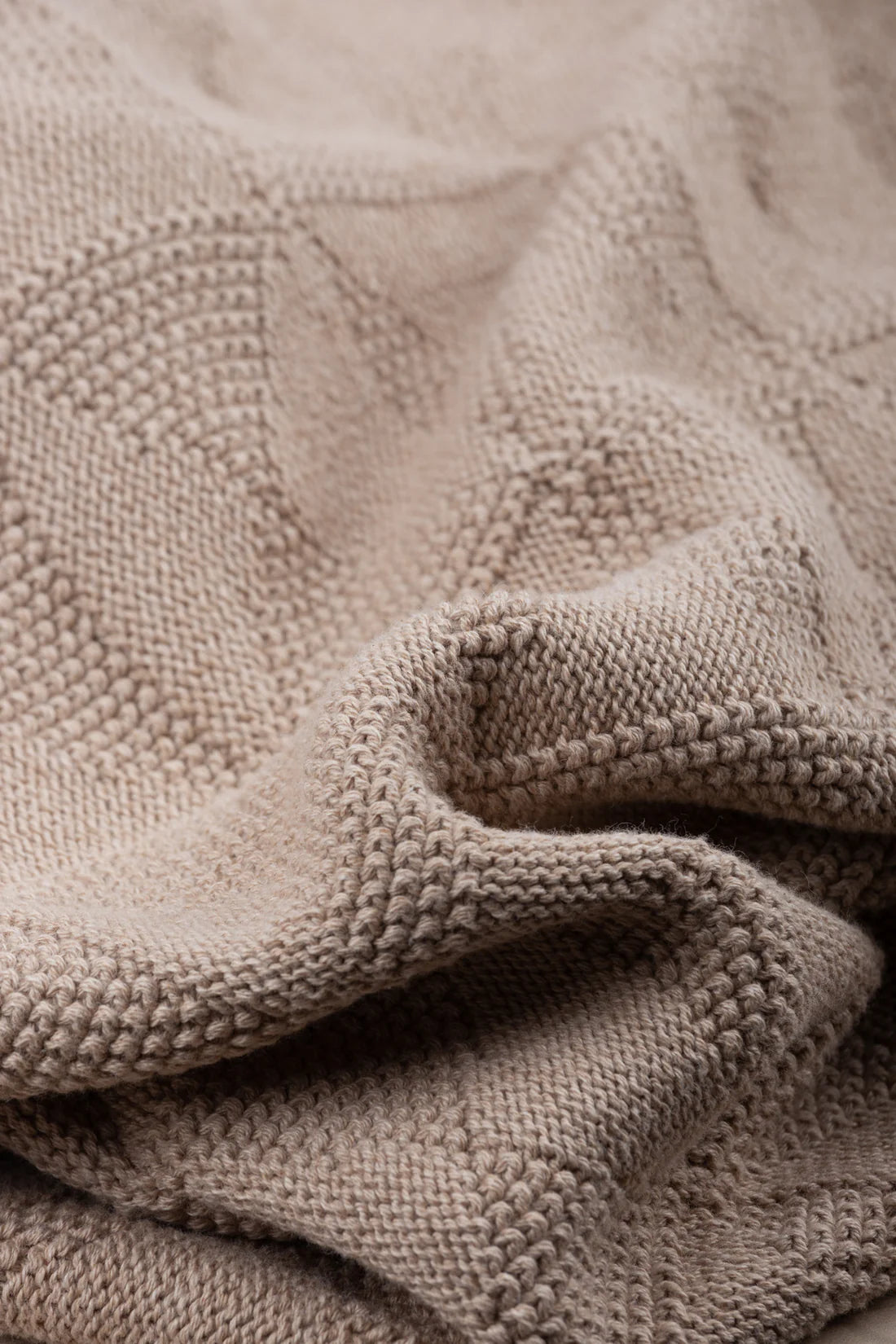 Close-up of a textured beige blanket with a diamond pattern