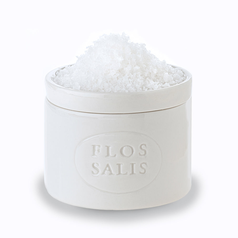 White container of Flos Salis with salt inside on a white background