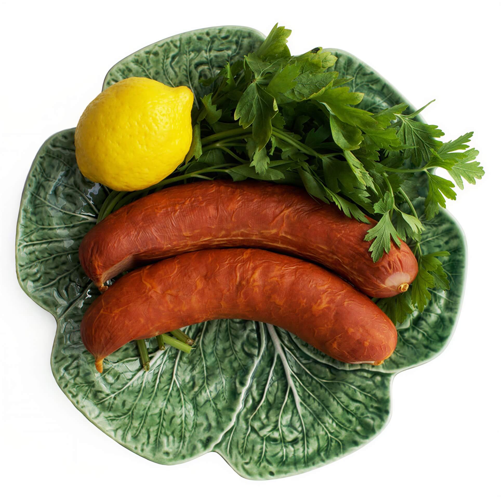 A traditional Portuguese sausage, Mild Chouriço, displayed on a plate with parsley, garlic, and an onion.